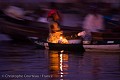 Marchande à bord de sa pirogue, marché flottant de la cité lacustre de Ganvié. 
Très tôt le matin, encore dans la nuit, les pirogues des femmes ne sont éclairées que par la lueur d'un lampion artisanal fabriqué avec une bougie sur une boite de conserve.
Bénin. Afrique 
 femme 
 Bénin 
 lagune 
 Ganvié 
marché
pirogue
marchande
bougie,
lampion,
 