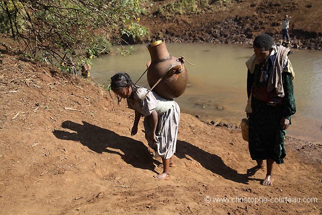 Young Girl Carrying Drinking Water on her back.
